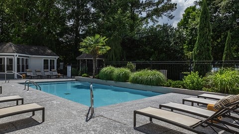 a swimming pool with lounge chairs and a house in the background